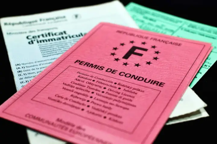 Permis de conduire et certificat d'immatriculation français posés sur une table